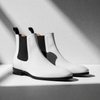 White Chelsea boots with black accents on a light gray background