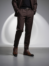 Person wearing a brown suit with a belt and shoes on a gray background