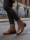 Brown leather boots worn on a street with graffiti in the background